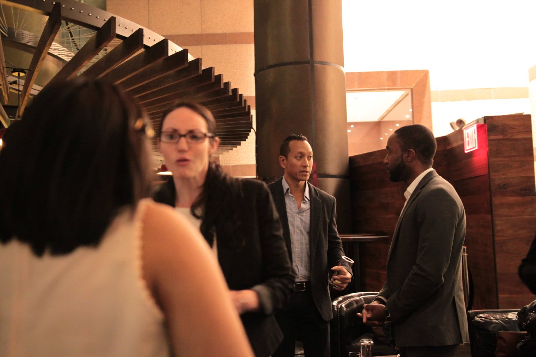 Independent consultants and professionals talking over drinks at a networking event in a dim lounge
