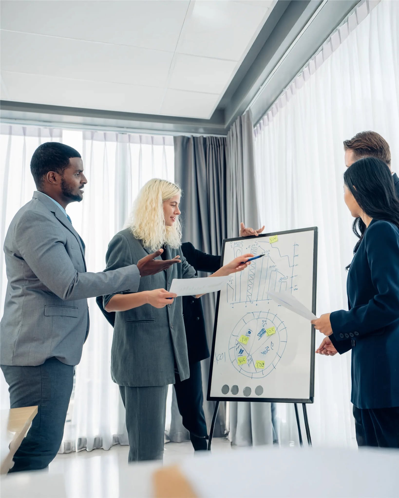 Consultants reviewing strategy charts on a whiteboard in a bright meeting room