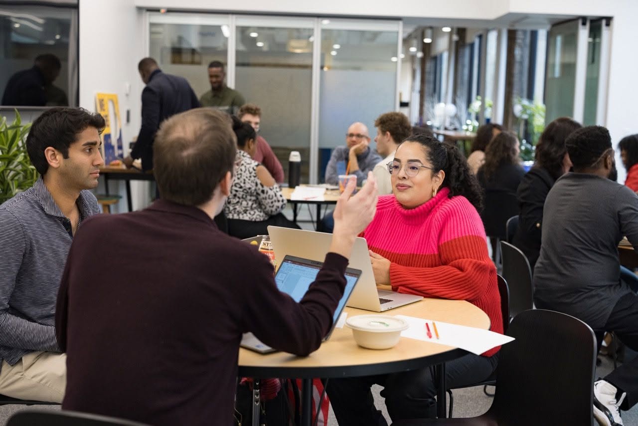 Consultants collaborating around a workshop table with laptops at a professional workspace