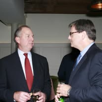 Two business consultants in suits talking at a professional networking event