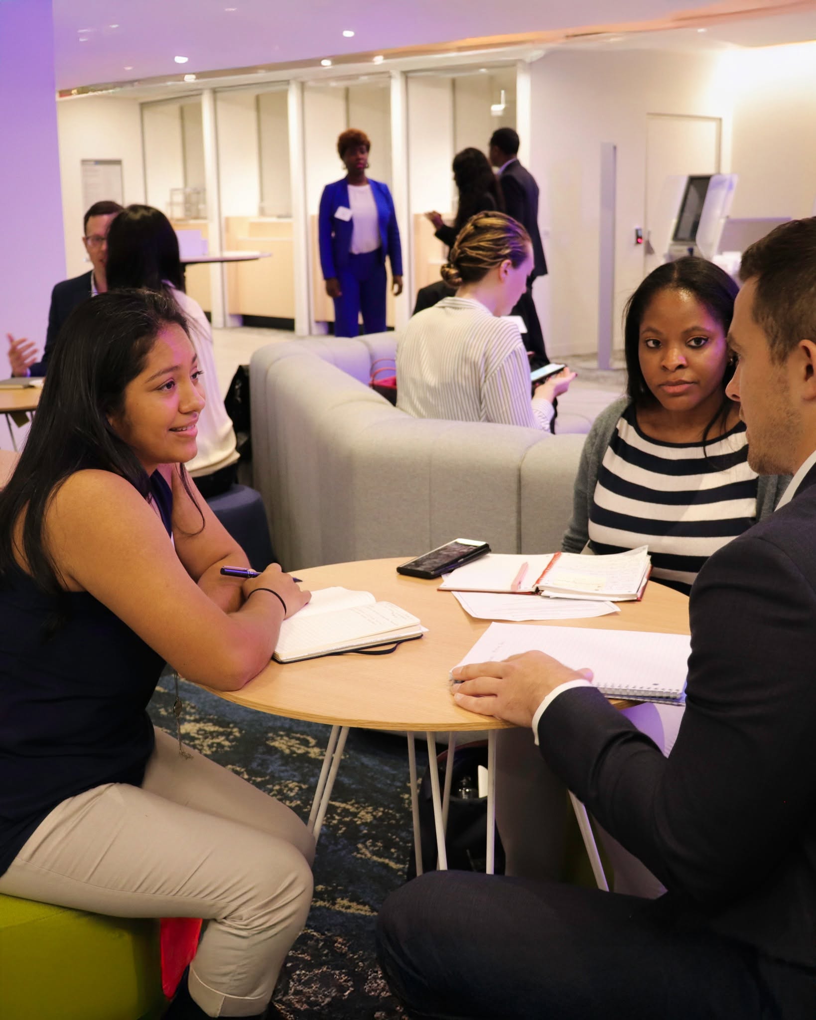 Independent consultants meeting clients across a table in a bright office lounge, taking notes