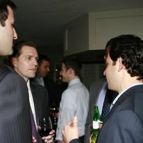 Consultants talking in small groups at a networking reception, drinks in hand
